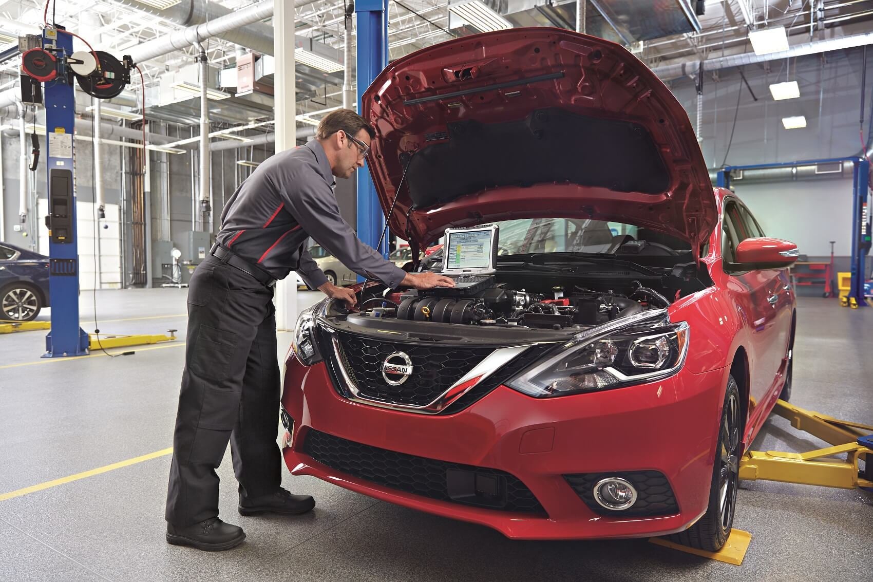 Nissan technician using a diagnostic tool at Salem Nissan Service Center in Salem, NH